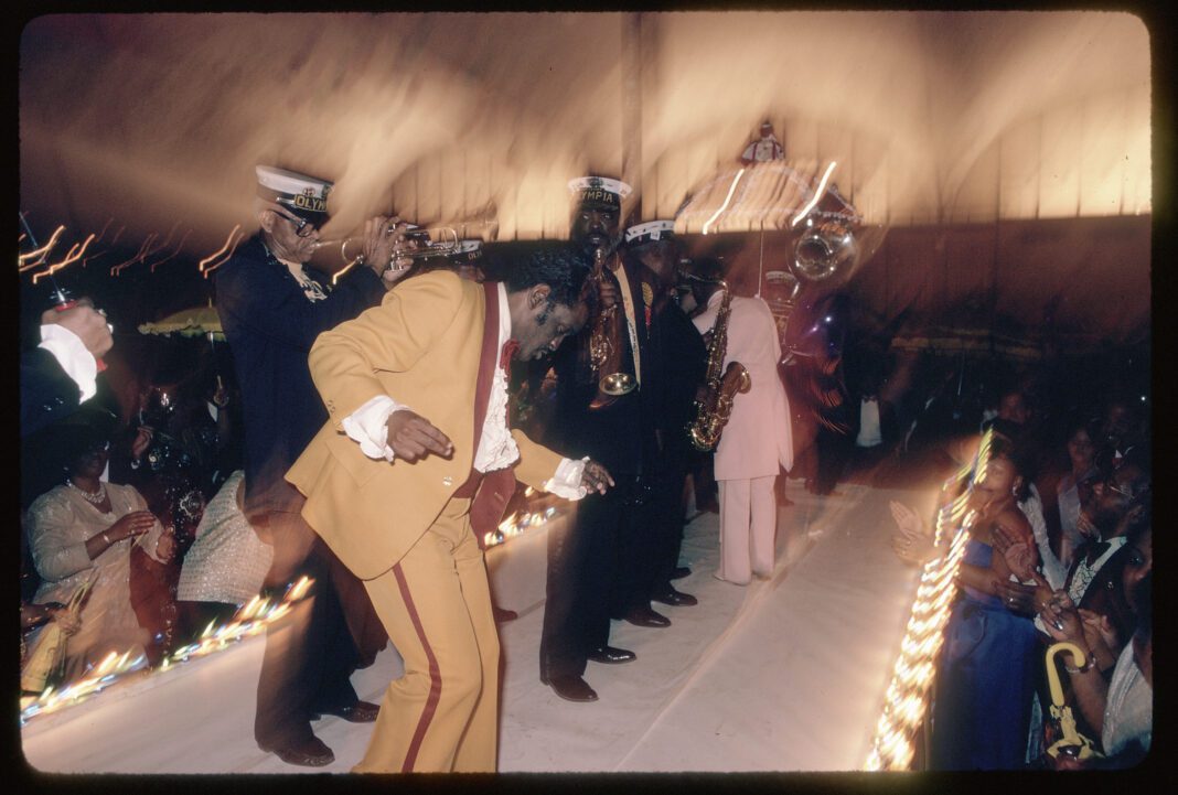 “Zulu Social Aid and Pleasure Club ball,” by Mitchel Osborne, depicts members of the Dejan’s Olympia Brass Band playing at a 1988 Mardi Gras ball. (THNOC; gift of Mitchel Osborne; 2007.0001.308 ©Mitchel Osborne)