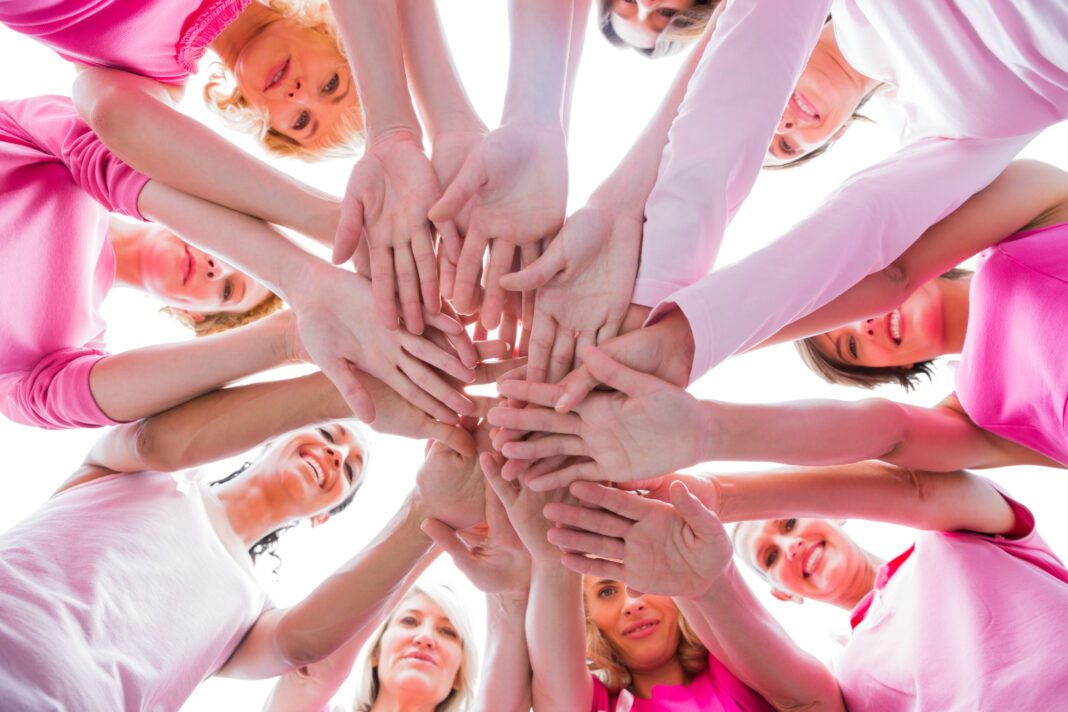 Diverse women smiling in circle wearing pink for breast cancer